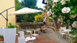 An outdoor patio area with white wicker furniture, a glass table, and a white umbrella.