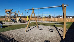A playground with swings and climbing structures. - Ferienwohnung im 1.Stock mit überdachter Terrasse und See- und Bergblick (Chieming)