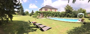 A stone house with a swimming pool, surrounded by a well-maintained lawn and trees. - Chambres Téranga (Pradines)