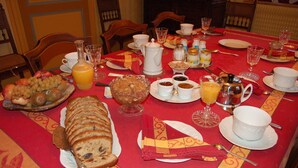 Una mesa de desayuno dispuesta con diferentes alimentos, como pan, frutas y bebidas.