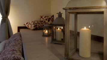 A cozy room with a bed, patterned pillows, and candles in lanterns.