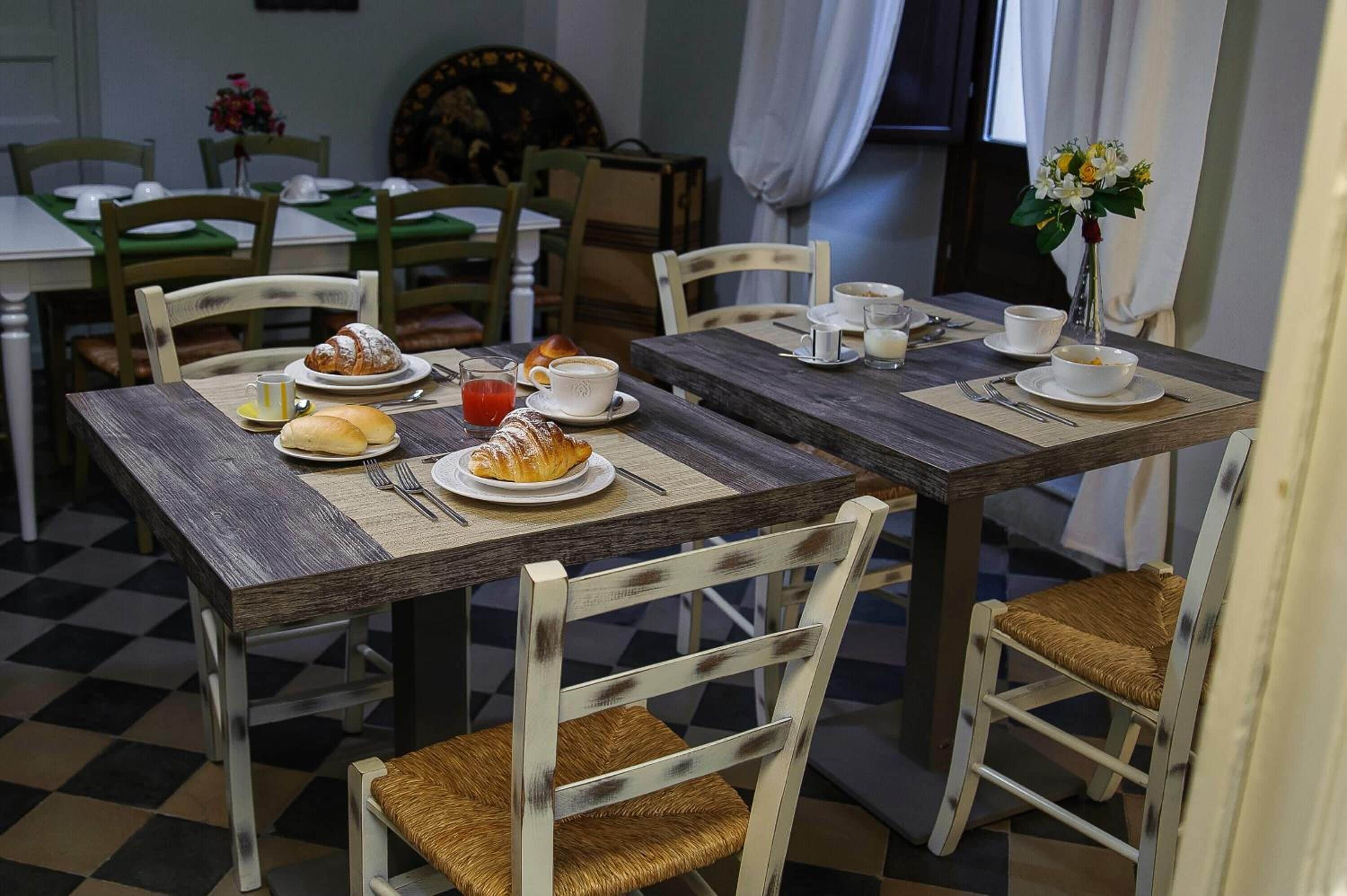 Un comedor con una mesa de madera dispuesta para el desayuno, que incluye croissants, una taza de café y un vaso de jugo.