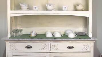 Un meuble blanc, de style vintage, doté de plusieurs étagères et tiroirs, où sont exposés divers ustensiles de cuisine et objets décoratifs.