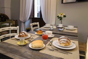 Una colazione con croissant, un bicchiere di succo e un vaso di fiori su un tavolo di legno.