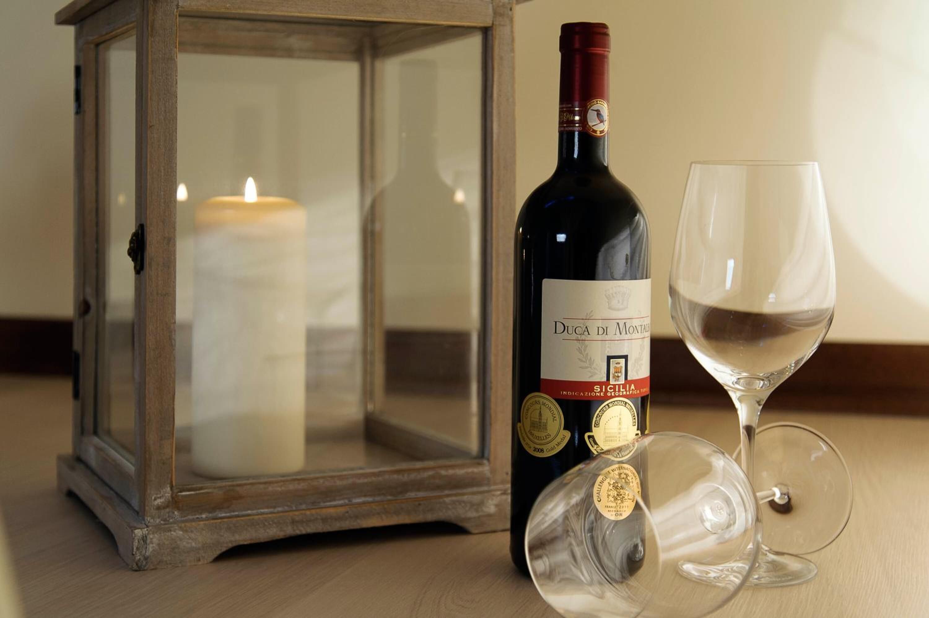 A bottle of Duca di Montalvo wine, a glass, and a candle inside a glass lantern.