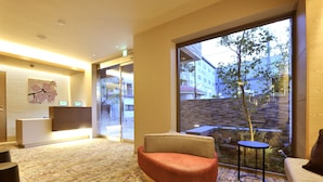 A modern hotel lobby with a large window, a reception desk, and a seating area. - RakutenSTAY×Shamaison Osaka Dekijima Station (Osaka)