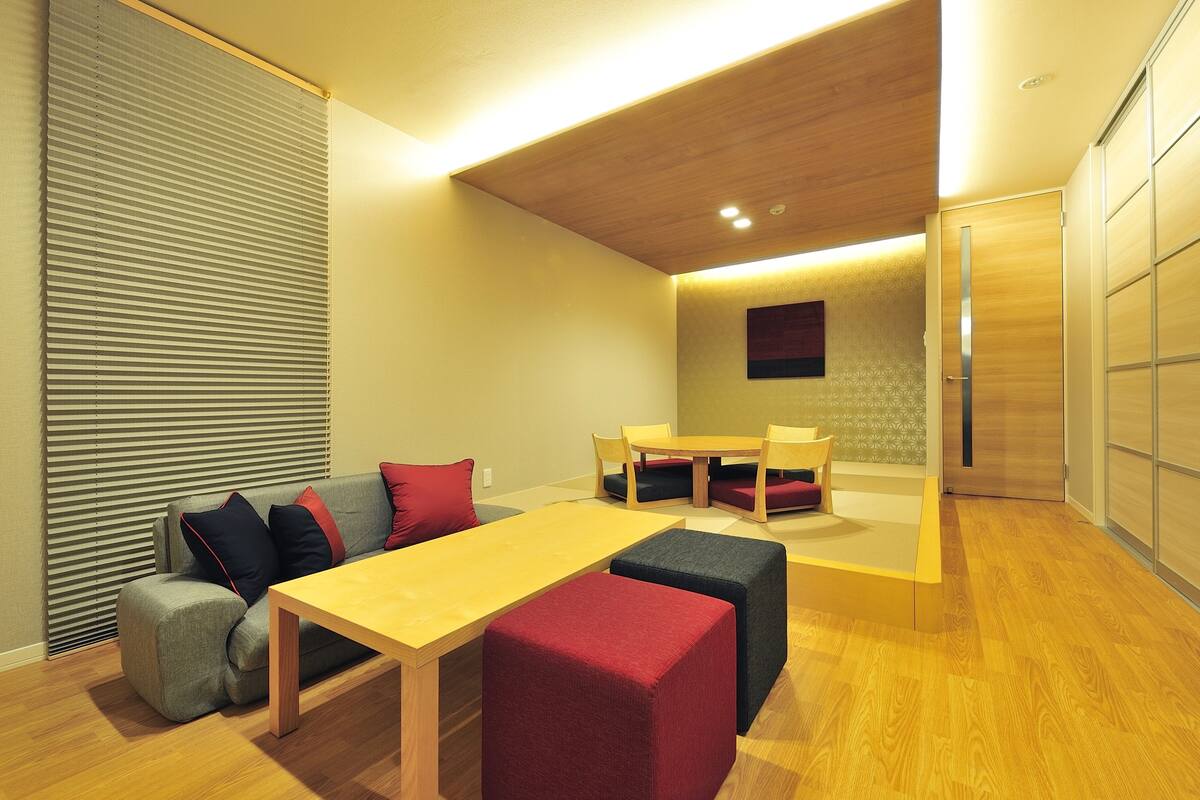 A modern living room with a wooden table, sofa, and ottomans.
