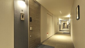 A hotel hallway with a carpeted floor, wooden doors, and a light fixture on the wall. - RakutenSTAY×Shamaison Osaka Dekijima Station (Osaka)