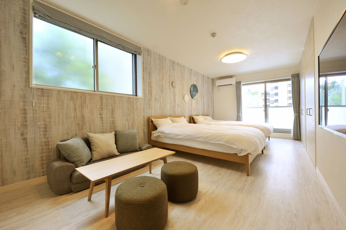A modern bedroom with a large bed, a sofa, and a bench.