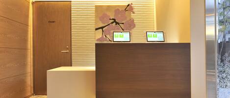 A reception desk with a wooden finish and a digital display.