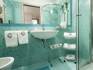 A bathroom with a white sink, a glass shower enclosure, and a tiled floor.