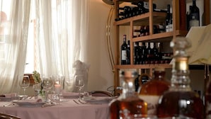 Una mesa de comedor dispuesta con copas de vino, una vela y una botella de licor.