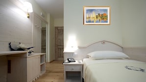 Un dormitorio con cama, mesita de noche, lámpara y un cuadro en la pared.
