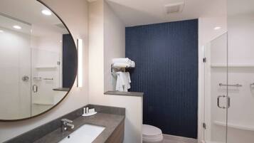A modern bathroom with a large mirror, a sink, a toilet, and a shower area.