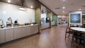 Une cuisine moderne avec un long comptoir, des armoires en bois et un mur d’accent vert. On peut lire sur le mur : « EST-CE QUE QUELQU’UN A PARLÉ D’EGGNOG ? »