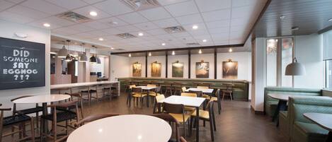 A restaurant interior with round tables, booths, and a bar area.