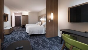 Une chambre d’hôtel avec un lit, un bureau, une chaise, une télévision et un miroir.