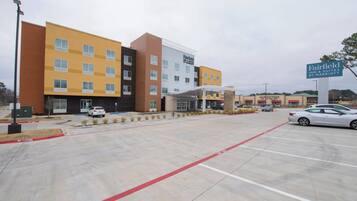 Un hotel a più piani con parcheggio e insegna per Fairfield Inn & Suites by Marriott.