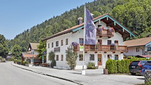 A traditional Alpine-style building with a balcony, a flag, and a mountain backdrop. - Alte Säge Ruhpolding (Ruhpolding)