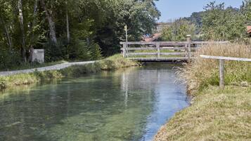 Une rivière paisible, avec un pont en bois et un petit bâtiment en arrière-plan.