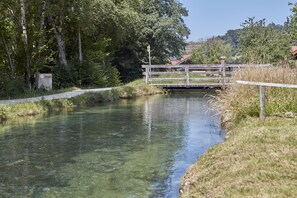 A calm river with a wooden bridge and a small building in the background.