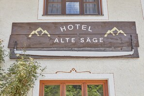 A wooden sign with the text "HOTEL ALTE SÄGE" above a window.