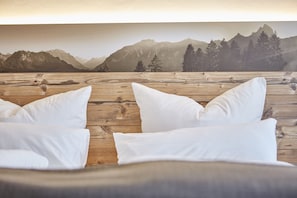 A wooden floor with white pillows and a mountain view.