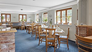 A dining area with wooden tables and chairs, potted plants, and large windows. - Alte Säge Ruhpolding (Ruhpolding)