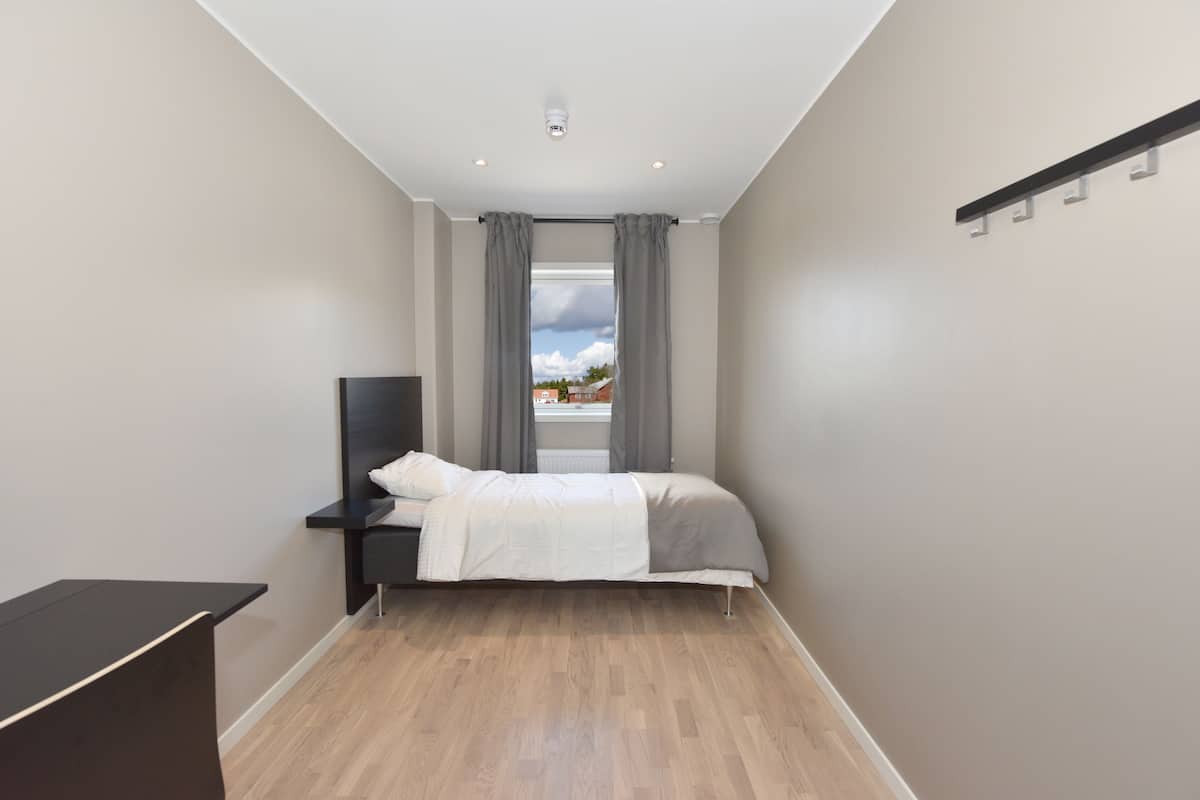 Un dormitorio moderno con cama, mesita de noche y televisor.