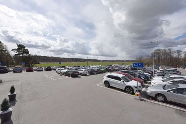 A parking lot with multiple cars and a few potted plants.