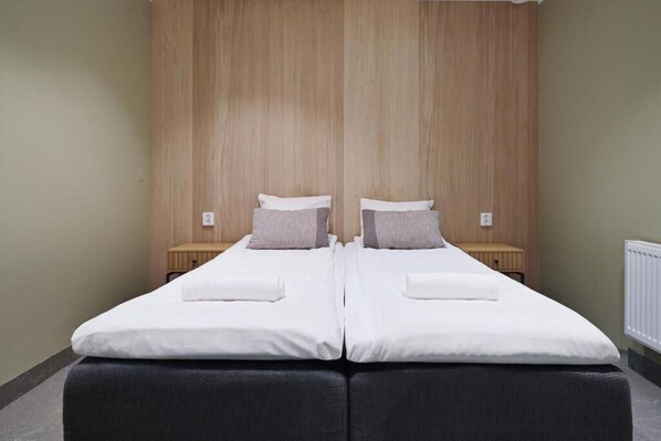 A double bed with white bedding and two pillows, a wooden headboard, and a small bedside table with a lamp. - Måby Park Hotel Arlanda (Marsta)