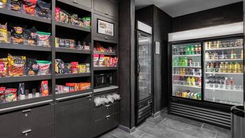 Zona de venta automática con aperitivos y bebidas, que ofrece varias opciones de comida y una sección refrigerada.