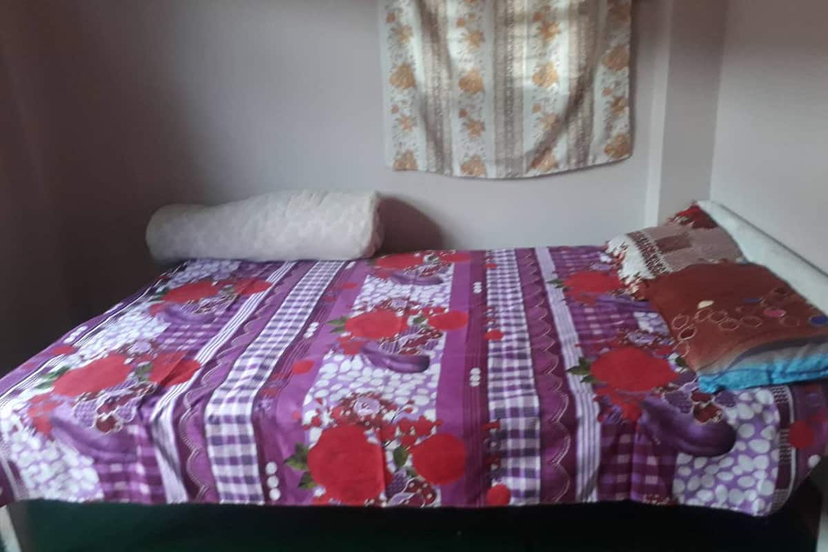 A bed with a floral-patterned bedspread and a rolled-up white blanket.