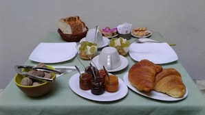 Una tavola per la colazione con croissant, pane, marmellate e un cestino di pane.