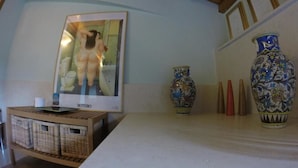 Una stanza con soffitto in legno, un quadro appeso al muro, un tavolino con cesti e vasi decorativi.