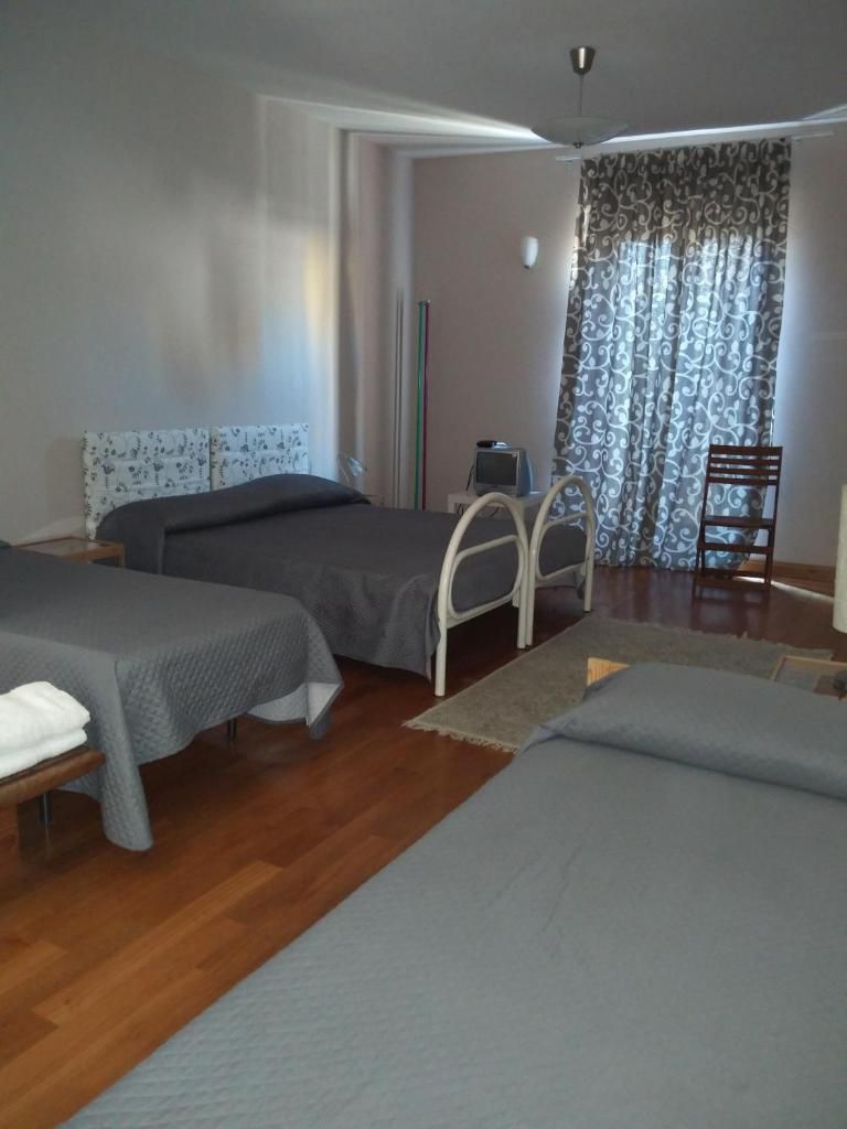 Una habitación con dos camas, un escritorio, una silla y un televisor.