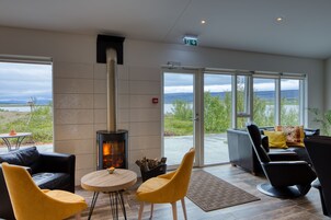 Un interior moderno con chimenea, zona de estar y ventanas amplias que ofrecen vistas al exterior.