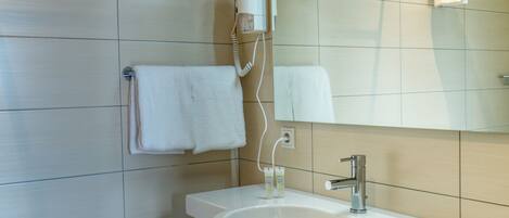 A modern bathroom with a white sink, a mirror, and a towel rack.