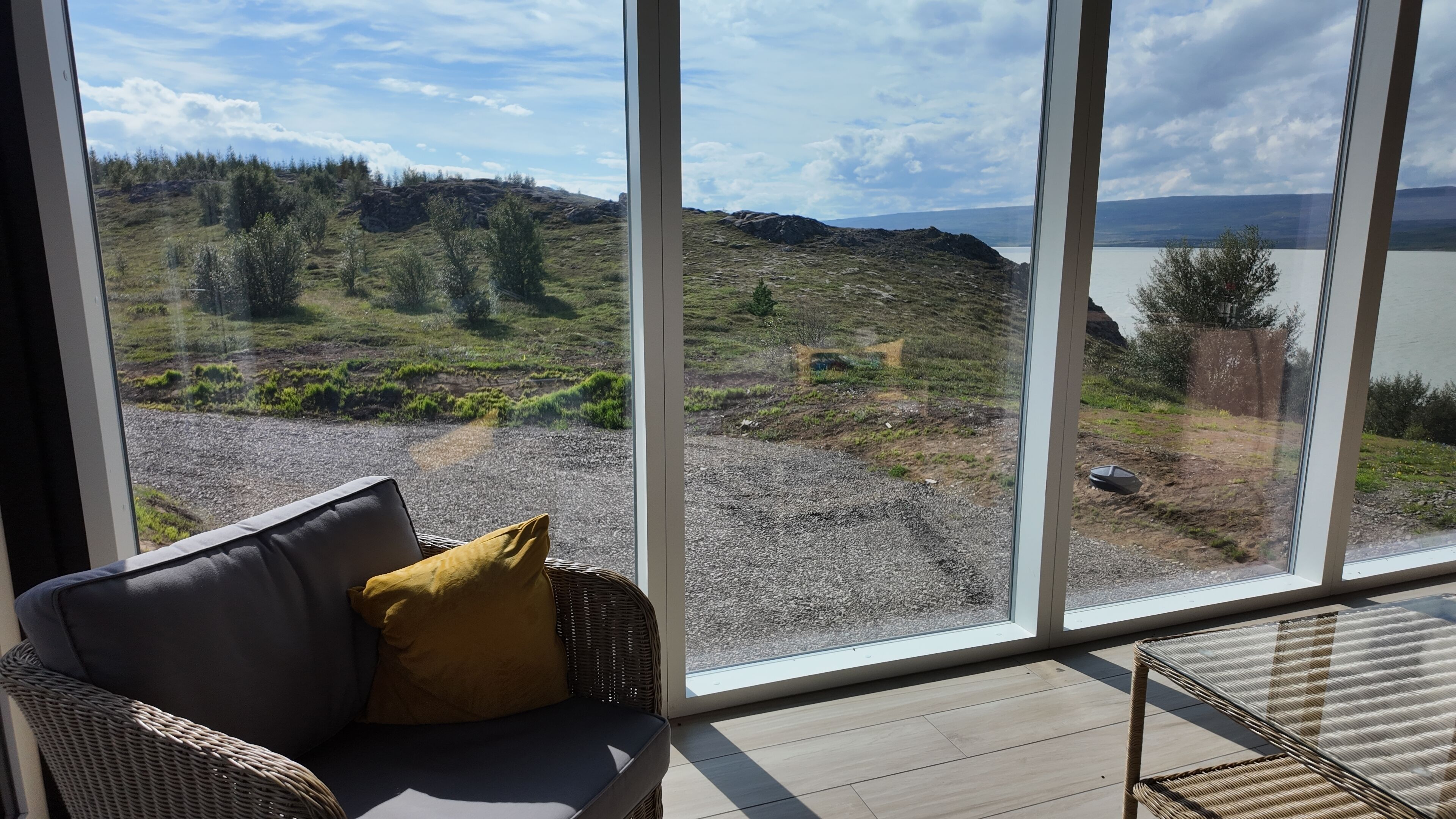 A room with a large window offering a view of a grassy landscape and a body of water.