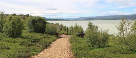 A gravel path leading to a body of water with a view of distant mountains.