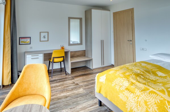 Una habitación de hotel con cama, escritorio, silla y armario.