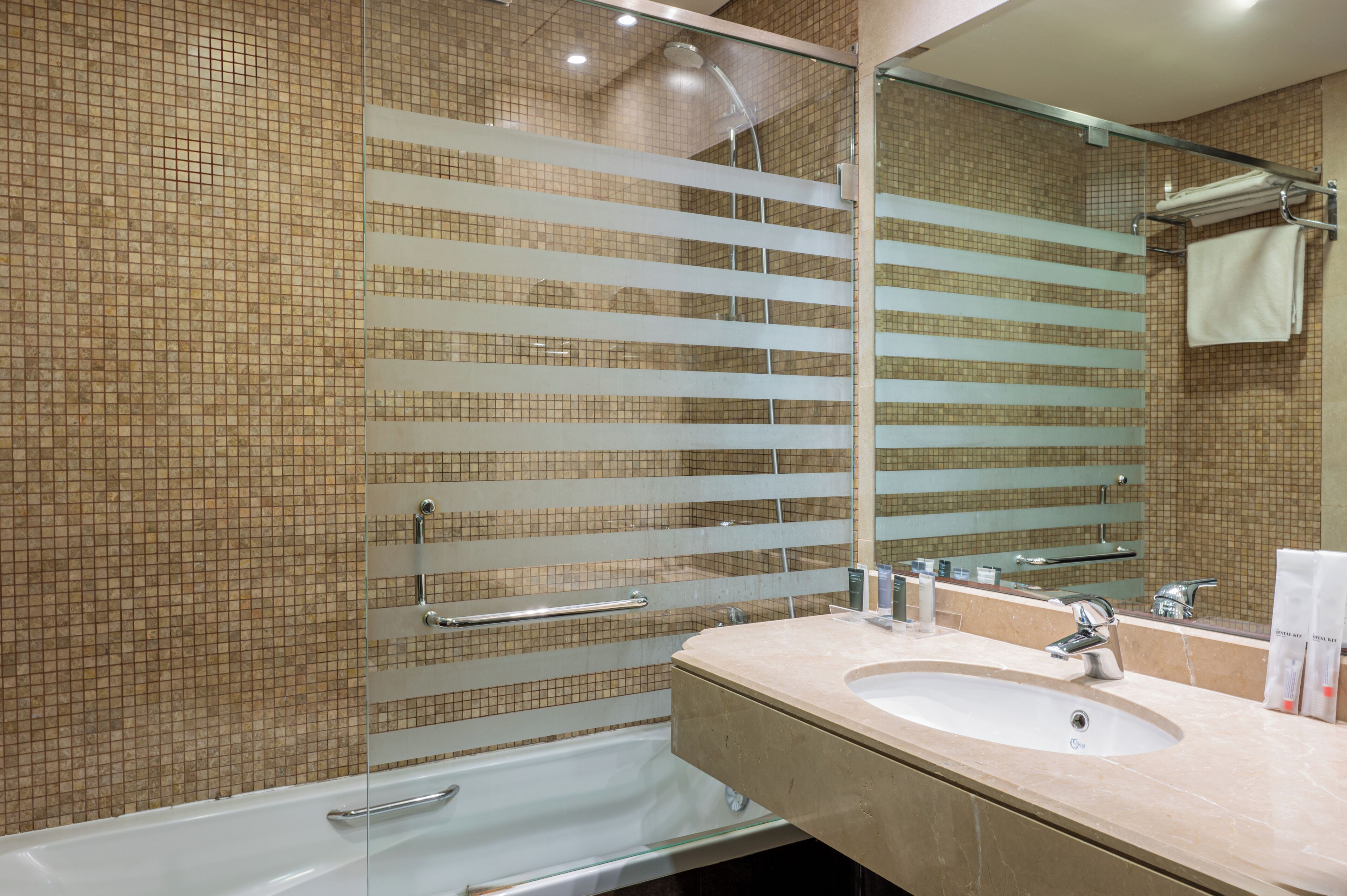 Un baño moderno con cabina de ducha de vidrio, un lavabo con espejo y pared de azulejos.
