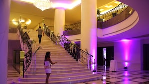 Una imponente escalera con diseño curvo, rodeada de columnas blancas y una barandilla decorativa.