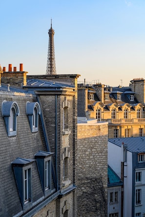Una hilera de edificios históricos con techos empinados y ventanas dormer, una imponente estructura de torre y cielo despejado.
