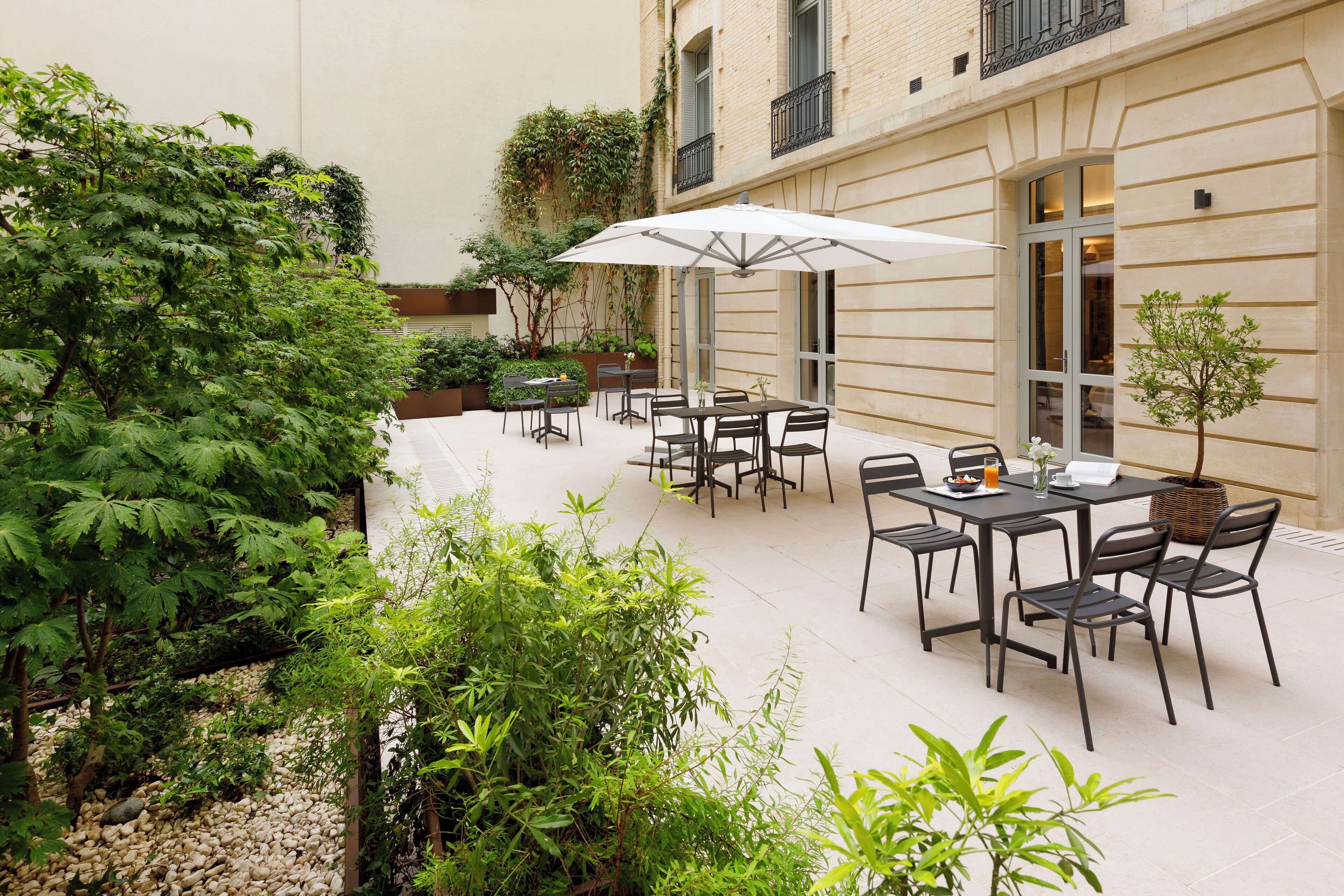 A courtyard with outdoor seating, a table with chairs, and a potted plant.