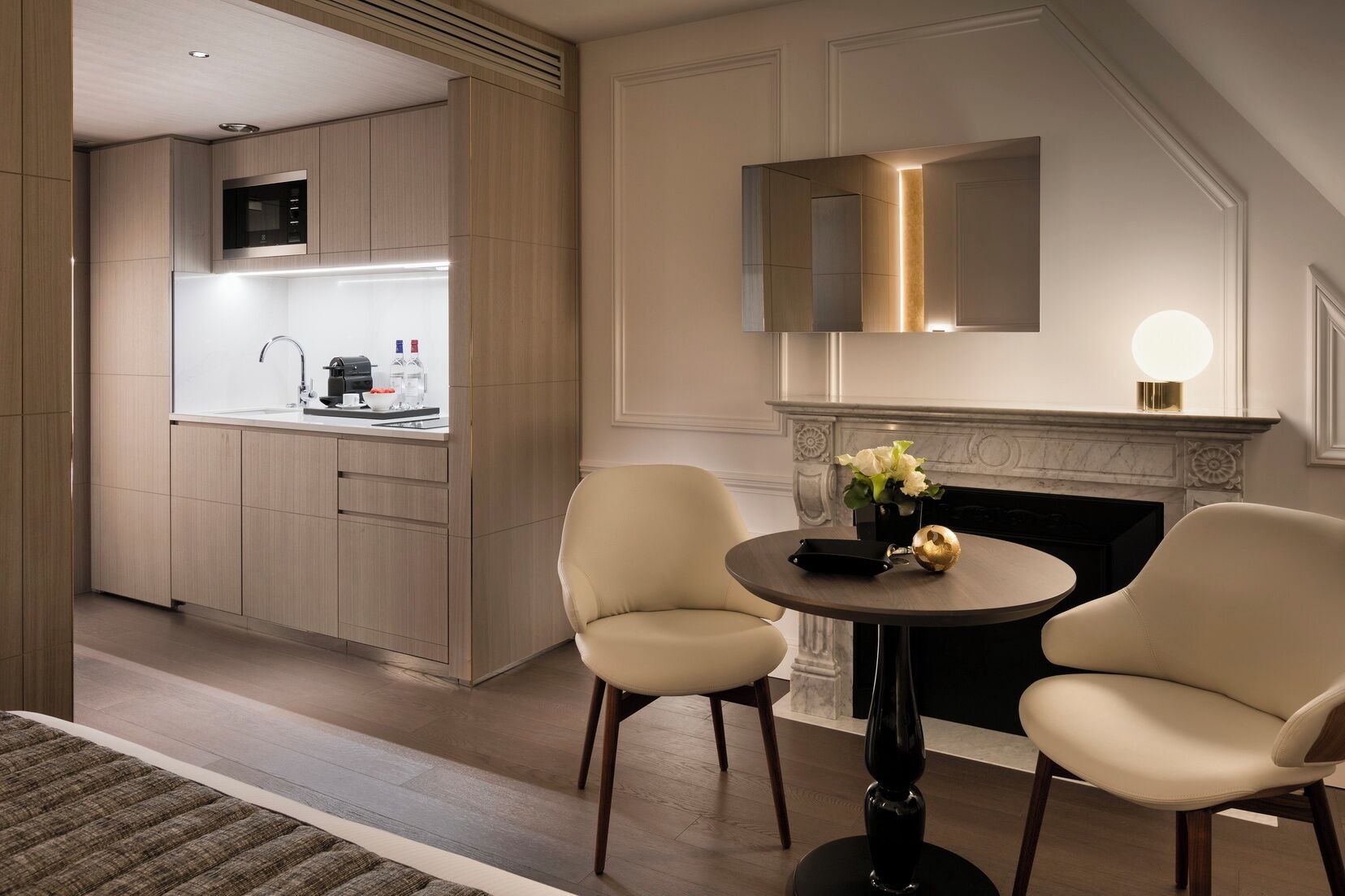 Una cocina moderna con armarios de madera, microondas integrado y un comedor con dos sillas y una mesa.