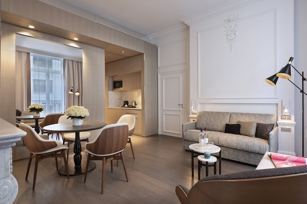 Una sala moderna con comedor, un sofá y una cocina al fondo.