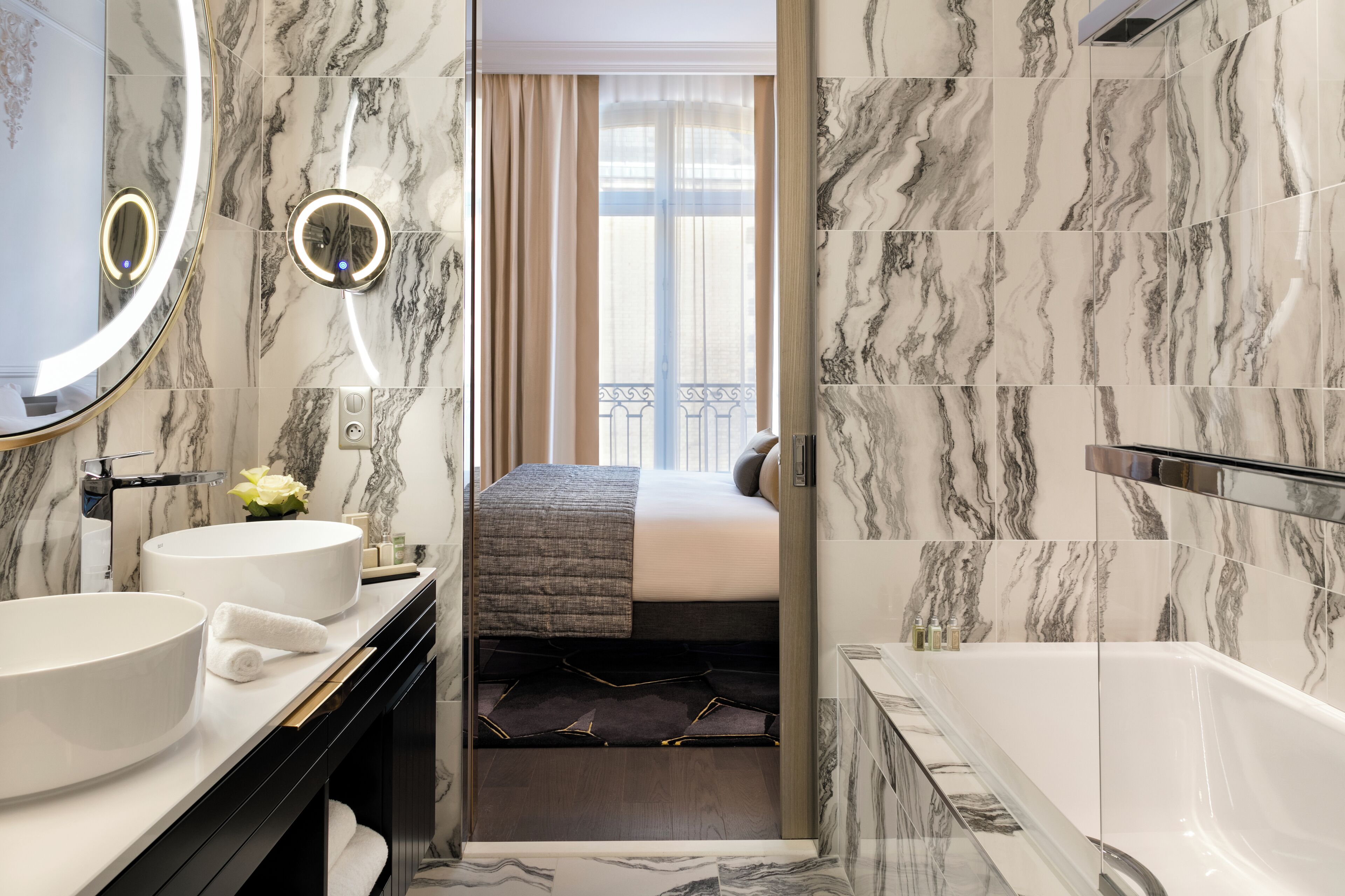 A modern bathroom with a bathtub, two sinks, and a large mirror.