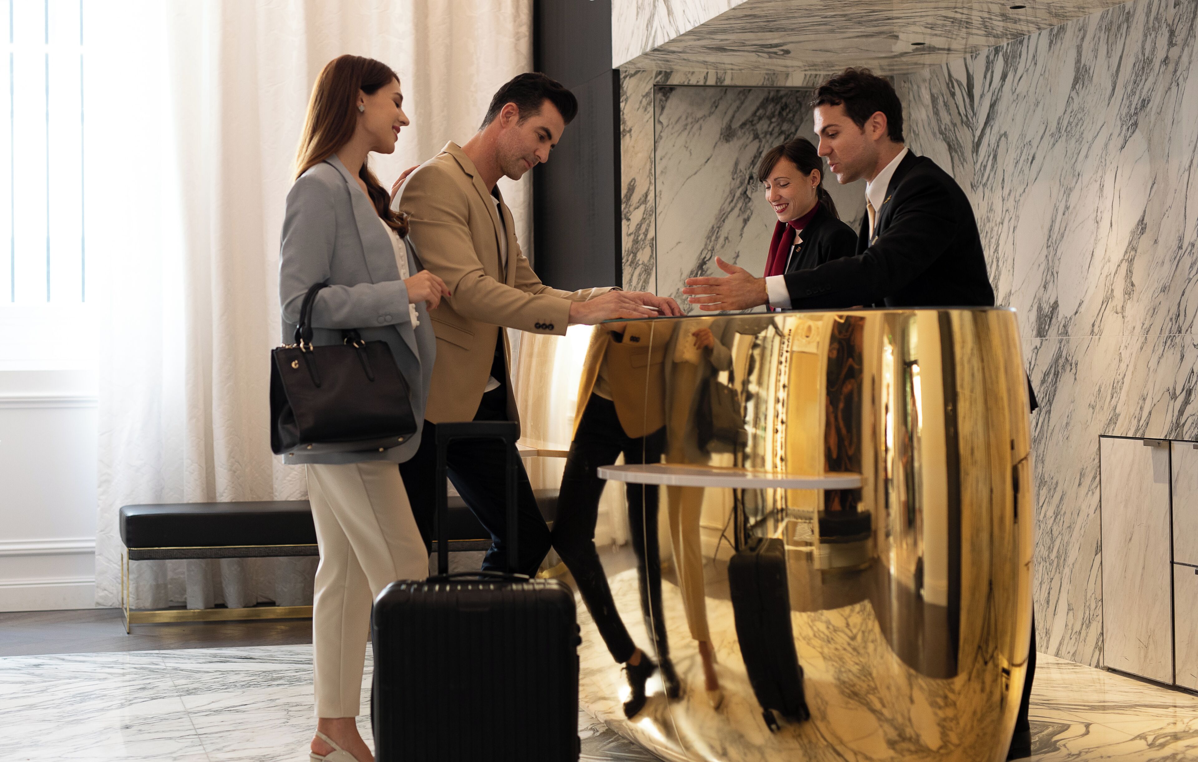 A reception area with a marble wall, a reception desk, and a black suitcase.