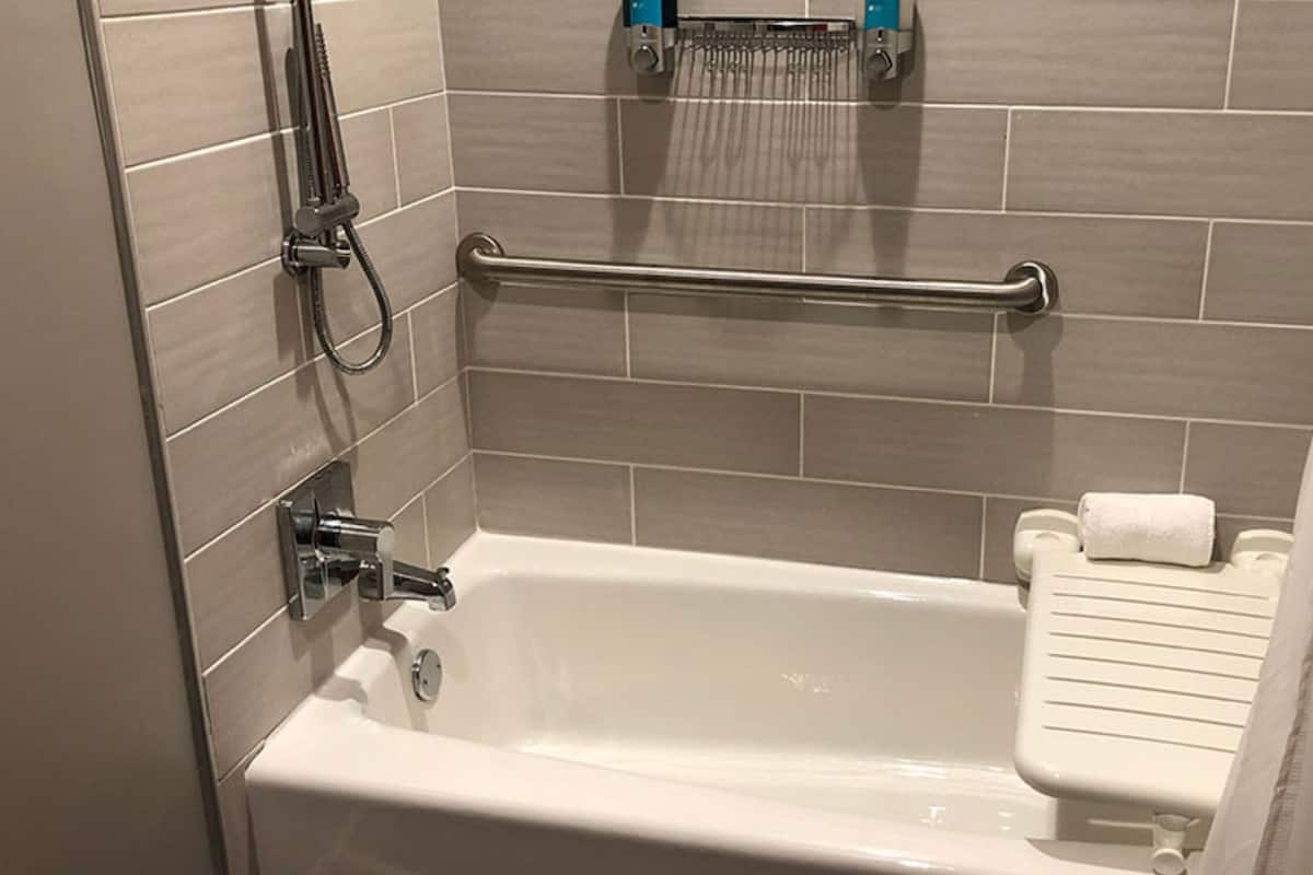 A bathroom with a bathtub, a hand shower, and a towel rack.